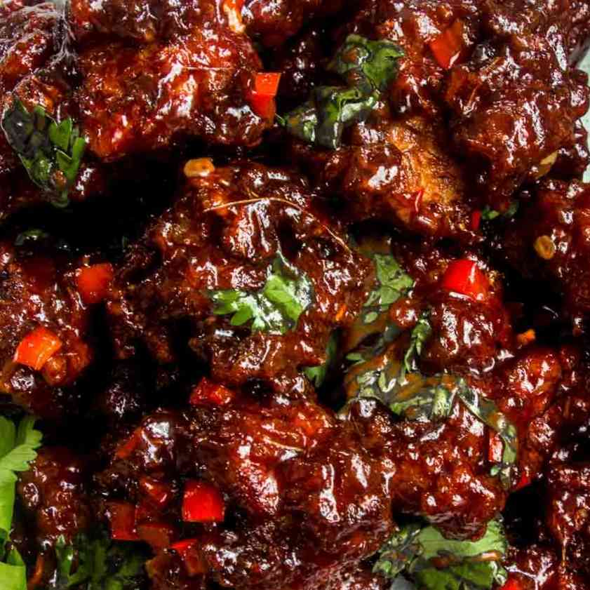 Delectable Chicken Manchurian dry with crispy fried chicken, vibrant vegetables, and a tantalizing blend of sweet and savory sauces, offering a delightful Indo-Chinese culinary experience